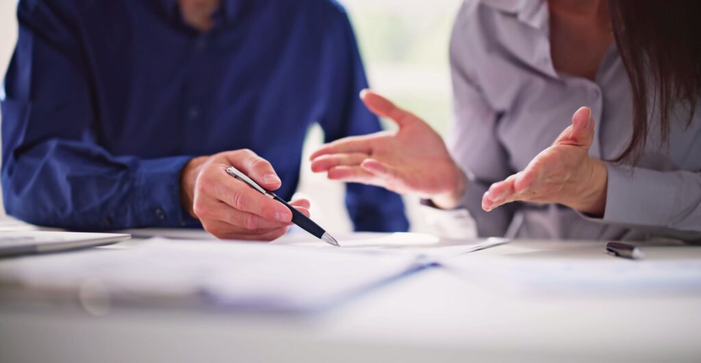 Two individuals annotating the document 'articles of association' inside an office.