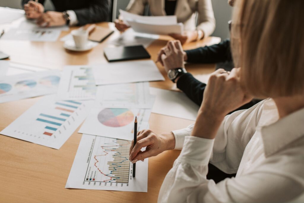A woman sitting in a board meeting with graphs spread on the table before her.