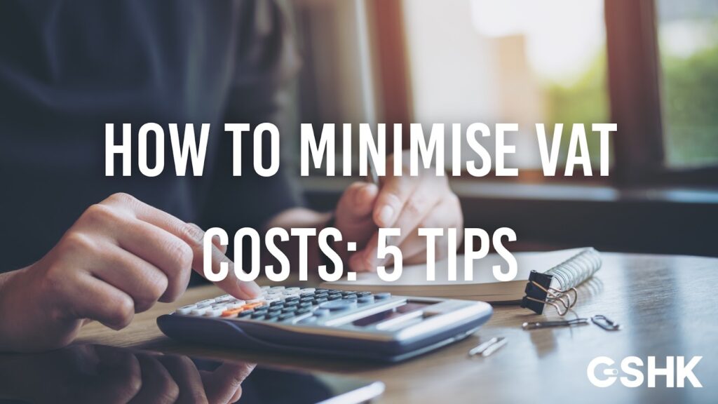 Cover image for 'How to Minimise VAT Costs: 5 Tips,' showing a person using a calculator and writing in a notebook on a wooden desk.