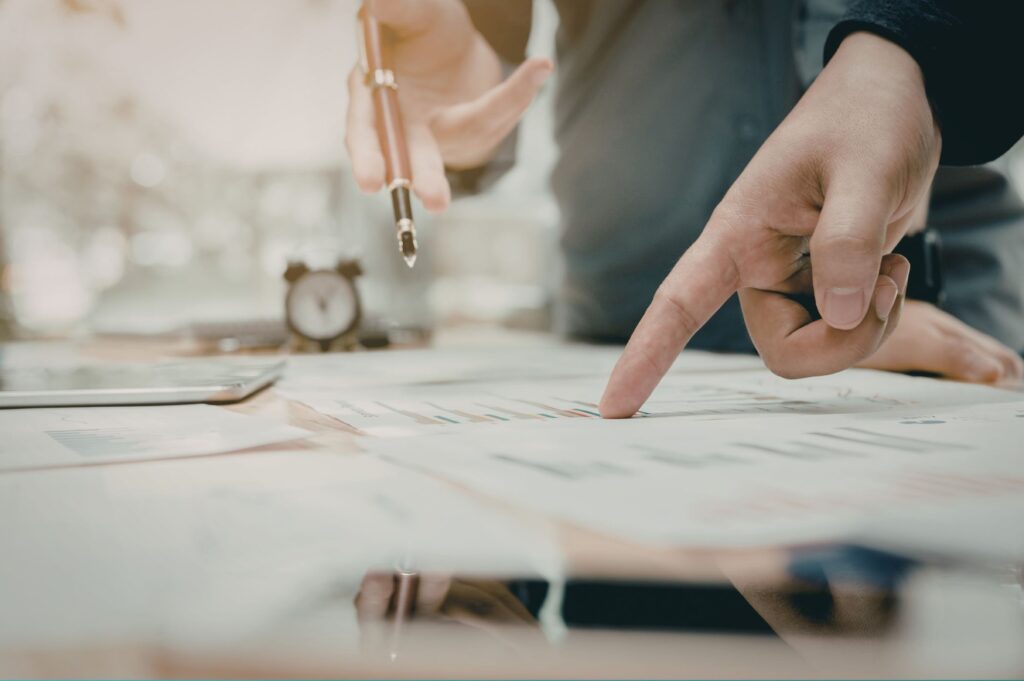 A few suited men checking company documents laid out on a desk.