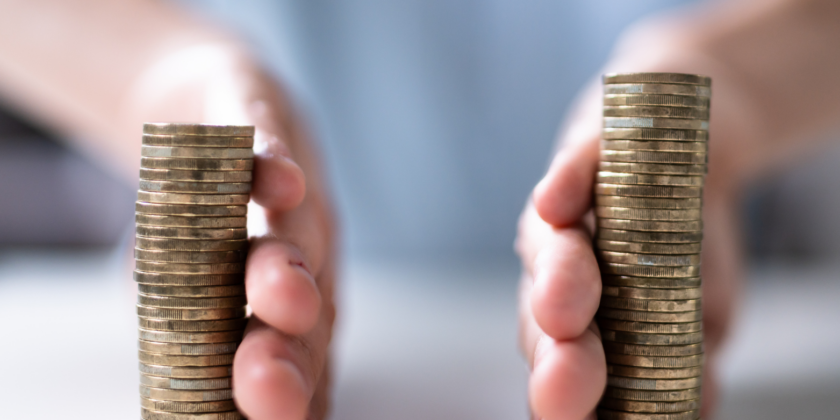 A Close-up Shot Of Two Stacks Of Gold Coins, With A Pair Of Hands On The Left And Right Side, Suggesting The Segregation Or Division Of Funds. The Background Is Blurred, Showing A Person In A Light Blue Or White Shirt. The Image Illustrates The Concepts Of A Segregated Account Or Segregated Funds.